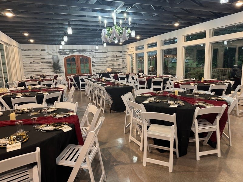 Hall set for a banquet with black linens and burgundy runners along the window wall