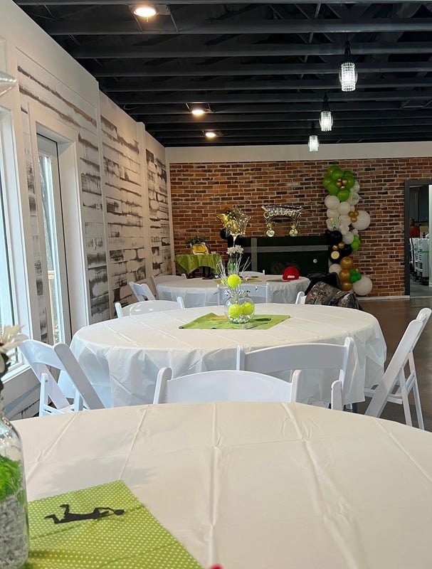 Round tables in white linen with green runners set inside the hall