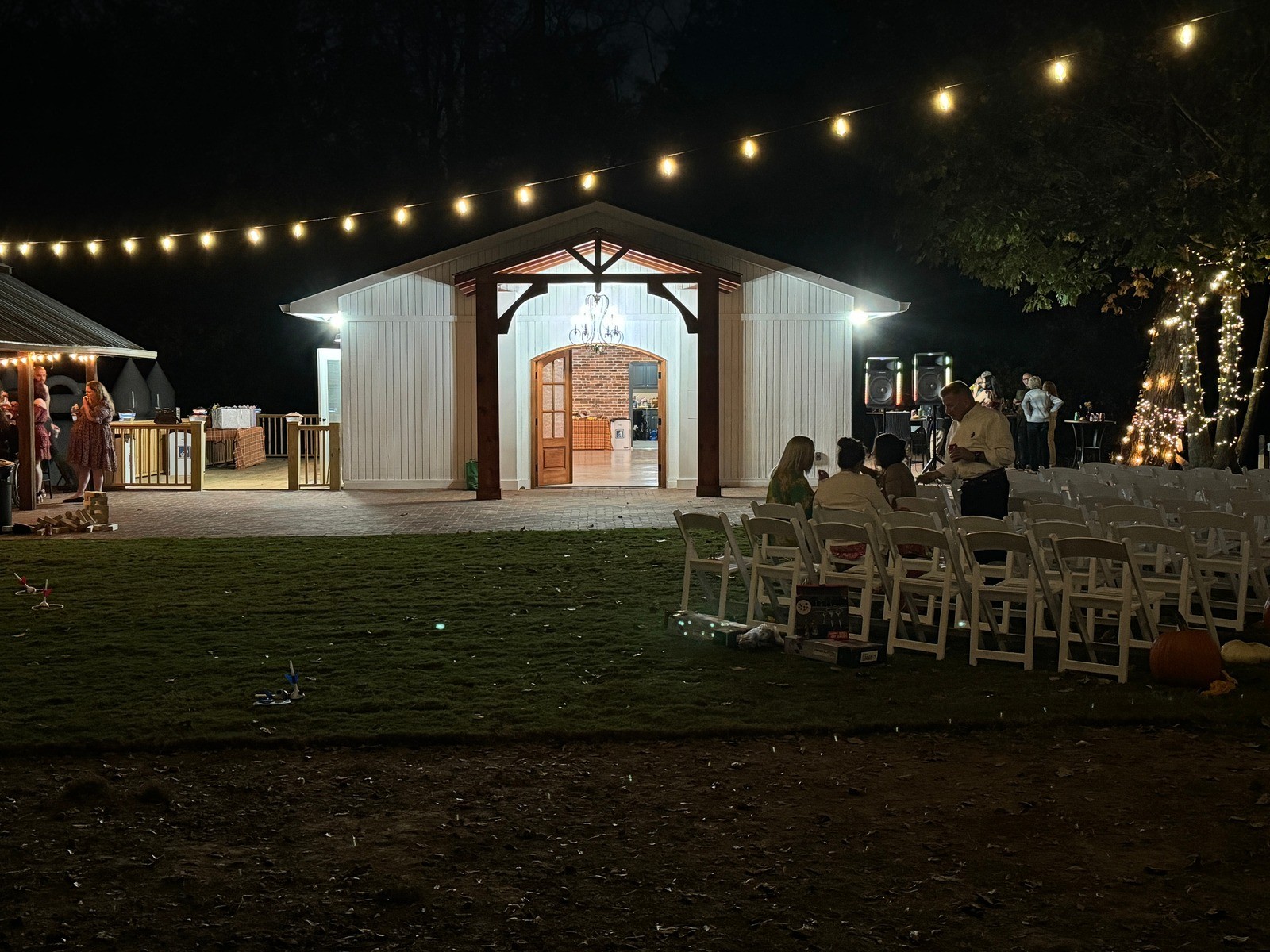 The Jericho Walls pavilion lit with string lights at night, with ceremony chairs set on the lawn