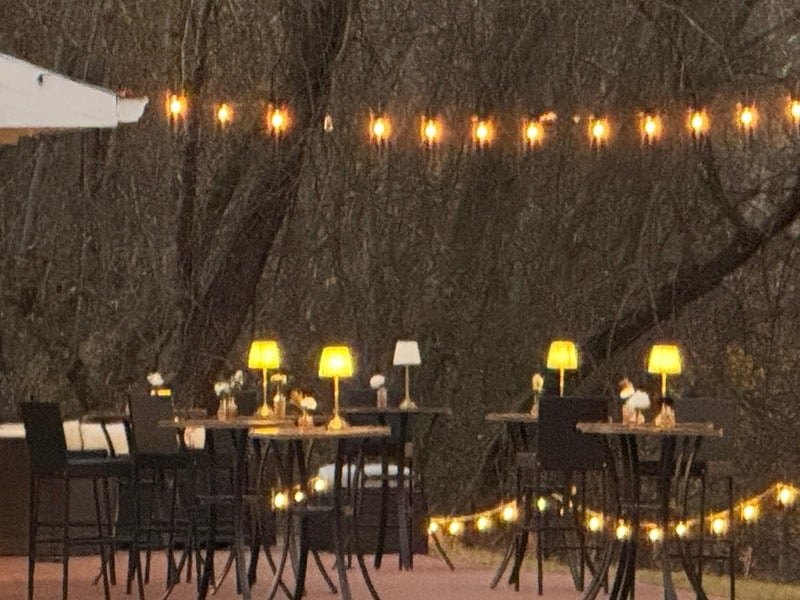 High-top tables with lamps on the courtyard under a canopy of lights