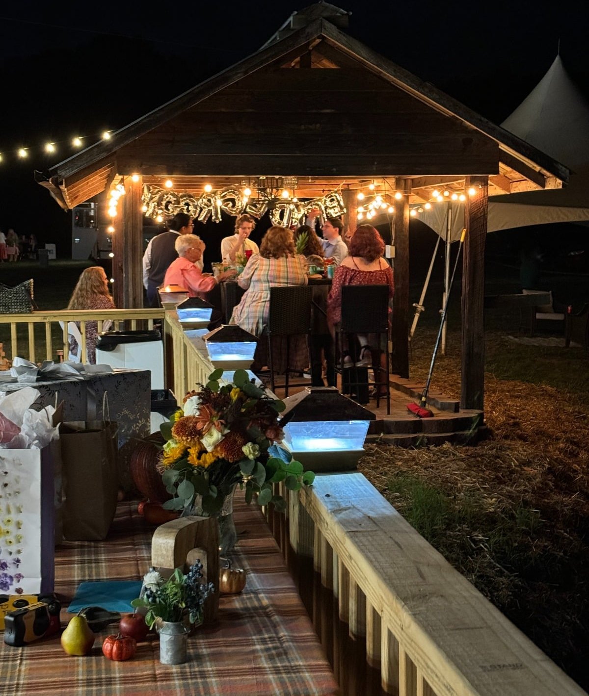 Guests seated under the pavilion strung with lights at night
