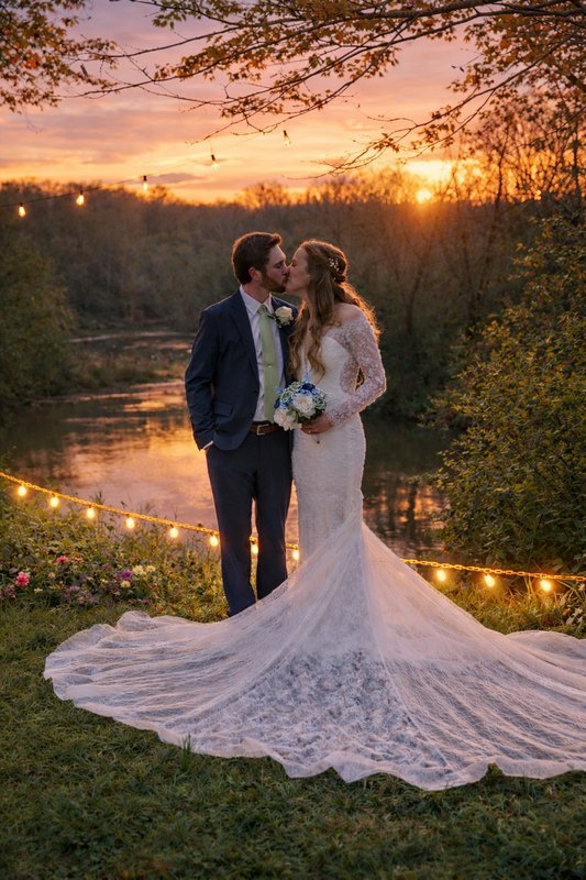 Couple by the river at sunset beneath string lights