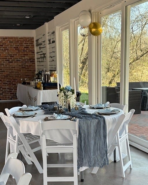 Guest tables with grey linens beside the window wall